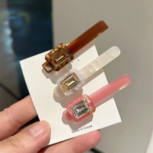 Three acetate hair clips in amber, white and pink colors with rhinestone rectangular inlay