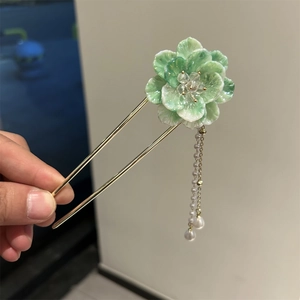 Détail d'un pic à cheveux floral avec pétales dégradés verts et glands de perles