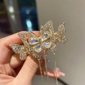 Détail d'une pince à cheveux papillon dorée avec strass et élégants longs glands