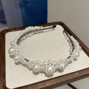 Elegant wide headband featuring layered white pearls on a dark base for a stylish bridal look