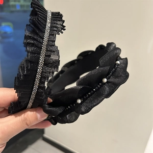 Dettaglio del cerchietto in rete nera con strass e fascia in tessuto con perle