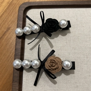Detail of vintage French rose hair clips with faux pearls and elegant black ribbon bows
