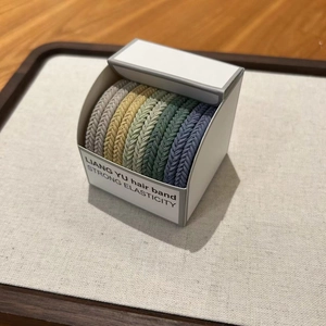 Close-up of high-elasticity braided hair ties in various colors inside a minimalist box