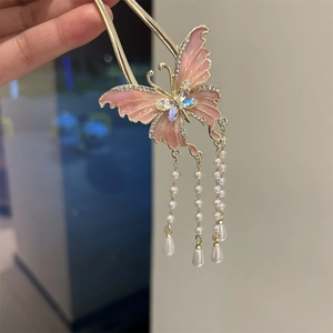 Detailed close-up of golden butterfly hair pin with pink tassels and inlaid rhinestones