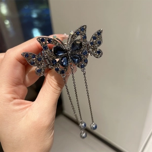 Détail de la pince à cheveux papillon bleu avec glands argentés et ornements en strass