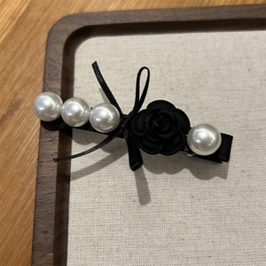 Detail of Korean style hair clip featuring a black camellia, ribbon bow and faux pearls