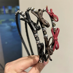 Macro shot showing thin headband details with sparkling rhinestones and leather bow