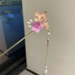 Detail of golden hair stick with pink butterfly wings, purple flower, and pearl tassels