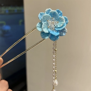 Détail d'épingle à cheveux fleur bleue avec chaînes dorées et perles blanches