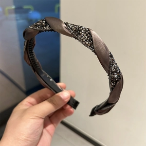 Detail view of coffee satin twisted headband with dark grey crystals and non-slip inner teeth