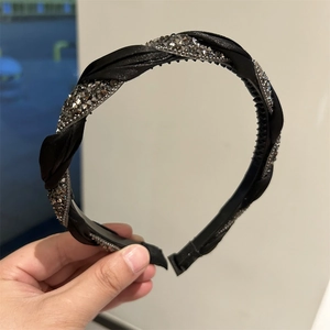 Close-up of twisted black satin headband with sparkling silver rhinestones