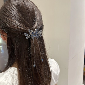 Détail d'une pince à cheveux papillon argentée avec strass bleus et pampilles fines