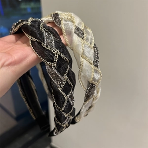 Dettaglio dei cerchietti intrecciati in rete con catene dorate e piccoli cristalli brillanti