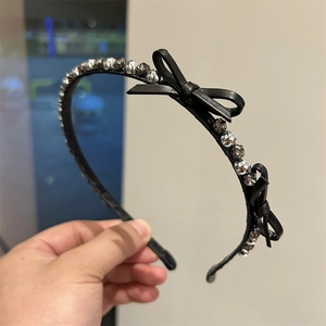 Close-up of black leather headband with double bows and sparkling rhinestone beads