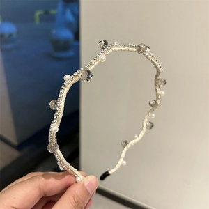 Detailed shot of woven crystal and pearl headband with cream ribbon and black tip covers