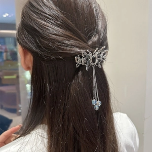 Pince à cheveux papillon argentée avec gemmes noires et glands sur cheveux sombres