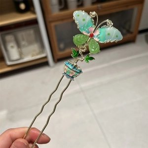 Detailed macro view of the butterfly tassel hairpin with green enamel and gold finish