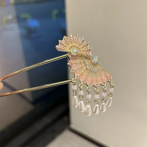 Detailansicht der goldenen Haarnadel mit Fächermotiven und weißen Perlenquasten