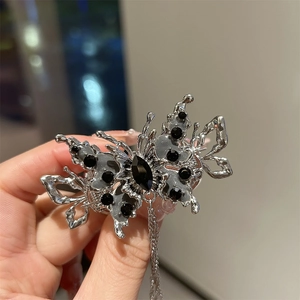 Détail de la pince à cheveux papillon argentée avec pierres noires et chaînes à glands