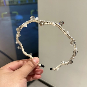 Detail of cream fabric headband with white pearls, grey crystals, and rows of fine rhinestones