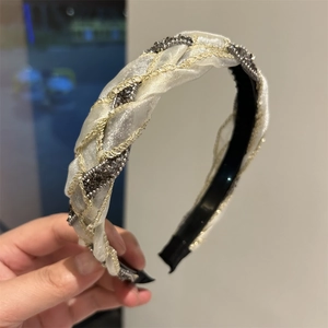 Dettaglio del cerchietto intrecciato in seta beige con ricami dorati e cristalli grigi