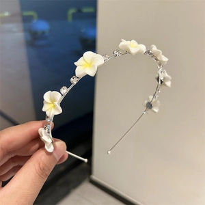 Serre-tête élégant orné de fleurs de frangipanier blanches et de strass brillants