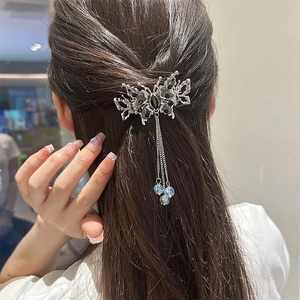 Détail de la pince à cheveux papillon argentée vintage avec pompons et perles