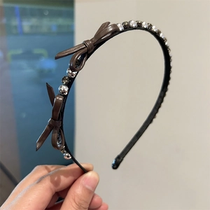 Close-up of brown PU leather bows and sparkling crystal beads on the black hairband