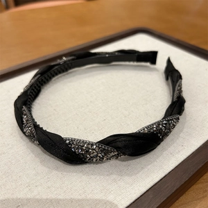 Close-up of twisted black silk headband with dark grey rhinestones on a display tray
