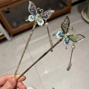 Detail of butterfly hair pins with elegant long tassels and pearl accents in hand