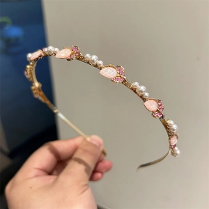 Dettaglio di elegante cerchietto dorato con cristalli a tulipano rosa e perle finte