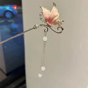 Detailed close-up of butterfly hair stick with enamel wings and tassel charms