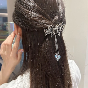 Détail d'une pince à cheveux papillon argentée avec strass noirs et chaînes à pampilles