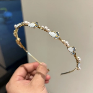 Dettaglio del cerchietto tulipano dorato con perle bianche e cristalli blu