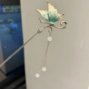 Close-up of enamel butterfly hair stick with gold tassels and turquoise wings