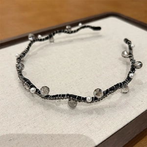 Close-up of black beaded headband with grey crystals and white pearls on fabric