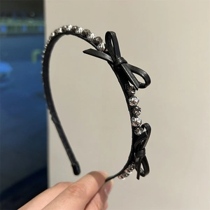 Close-up of black leather headband with sparkling rhinestones and double bow details