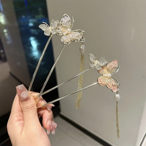 Detail of golden butterfly hairpins with tassels, faux pearls and enamel inlay