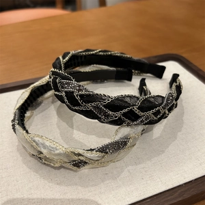 Dettaglio di un cerchietto intrecciato con strati di rete, catene metalliche e strass luminosi