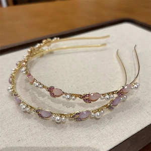 Dettaglio di cerchietti dorati eleganti con motivi floreali in pietre rosa e viola