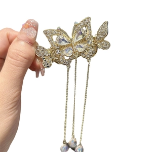 Pince à cheveux papillon dorée avec glands et strass sur un fond blanc neutre