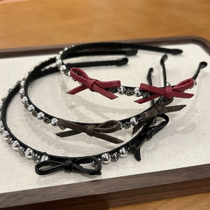 Close-up of three crystal bow headbands in red, brown and black on a wooden tray