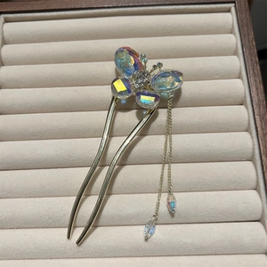 Detailed macro view of an iridescent butterfly hair pin with cascading gold tassels
