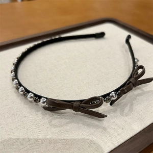 Detail of elegant bow headband with silver metallic beads and brown leather finish