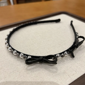Close-up of black leather headband featuring silver beads and delicate bow accents