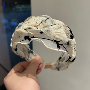Dettaglio del cerchietto in chiffon intrecciato con motivi astratti e stelle dorate