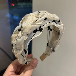 Dettaglio di un cerchietto in tulle intrecciato beige con stampe di farfalle e cristalli