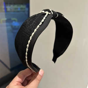 Detail of black fabric headband with white contrast stitching and twist knot design