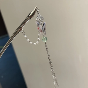 Detailed close-up of a silver hairpin featuring a colorful butterfly pendant and long tassels