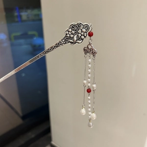 Detail of silver vintage hair stick featuring floral relief and pearl tassel charms